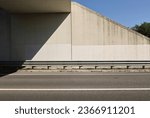 Guardrail in protection of sidewalk and concrete wall of an underpass. Two lane road in front. Background for copy space