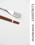 Small photo of Wooden pairs of chopsticks and cake fork on white background. unconstrained fork vs constrained chopsticks with copy space.