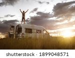 Man with raised arms on top of his camper van