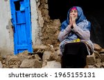 Small photo of Praying old woman. Old grandmother in prayer portrait photo. Grandmother prays against the background of the ruins. Poverty and destitution. Old face of grandmother in prayer.
