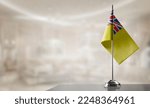 Small photo of A small Niue flag on an abstract blurry background.