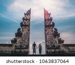 Happy young couple staying in temple gates of heaven and holding hands of each other. Perfect Honeymoon concept.  Lempuyang Luhur temple in Bali, Indonesia.