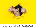 Small photo of Female ear and two hands close-up. Copy space. Torn paper, yellow background. The concept of eavesdropping, espionage, gossip and the yellow press.