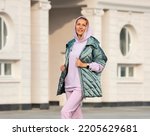Fashion women clothes. A woman in a warm oversized vest and a lilac hooded sweatshirt. Elegant comfortable clothing for sports and walks.