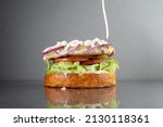 Small photo of Burger with onions and mayonnaise, on a gray metal table. Without the top, the bun is poured with mayonnaise.