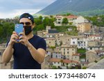Young man taking a photo with iPhone 12 pro max in Italian town