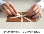 Small photo of tie ribbon on gift certificate. woman hands hold handmade bronze envelope with bow
