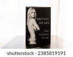 Small photo of San Diego, CA - November 8, 2023: Britney Spears memoir "The Woman in Me" stood up on a table in front of a white background.