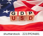 Small photo of GDP or gross domestic with wooden cubes or blocks on the American flag background. Business and growth of GDP, domestic product concept. Top view