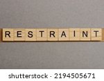 Small photo of text the word restraint from brown wooden small letters with black font on an gray table