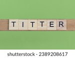Small photo of word titter made of small gray wooden letters on a green paper background