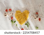 Food valentine concept. Pasta in shape of heart on light pink background. Heart mark (healthy love) made with mini tomatoes