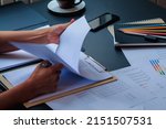 Small photo of An accountant is examining a large amount of income and expense documents laying on their desks in their offices to summarize their annual results. Accounting concepts to summarize earnings