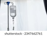 Small photo of An iron stand to hang saline bottle high to deliver saline via catheter to an intravenous patient lying on patient bed. Medical concept in which doctor gives saline solution to patient through vein
