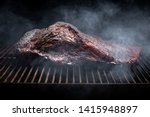Smoke rising around a slow cooked beef brisket on the grill grates of a smoker barbecue, in a grilling concept with space for text on top and bottom
