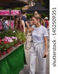 Small photo of London, UK - July, 2019. Young people shopping for flowers and plants on a florist stall in Brockley market, a local farmer's market held every Saturday in South-East London.