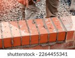 Small photo of Close up of a brick wall and jointer trowel used by the worker to apply and level the mortar between bricks. Bricklayer making finishing touches to the brick wall and filling joints with mortar