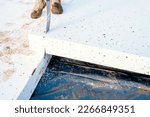 Small photo of Builder placing polystyrene insulation boards on waterproofing membrane during floor construction. Energy saving concept