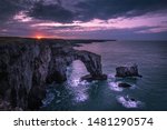 Sunrise over Green Bridge of Wales, famous, natural rock arch, popular landmark and tourists attraction.Colourful sky above dramatic coast of Pembrokeshire,South Wales, UK.Scenic british landscape.
