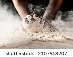 Small photo of Clap hands of baker with flour. Beautiful and strong men's hands knead the dough make bread, pasta or pizza. Powdery flour flying into air.
