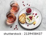 French cuisine. Baked camembert cheese with cranberries and basil leaves, wine on a light background, banner, menu, recipe place for text.