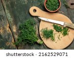 Chopped fresh dill on a cutting Board and a bunch of dill preparation for freezing serving size organic healthy ething natural product portion on a wooden table. Top view,