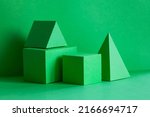 Small photo of Abstract geometrical figures still life composition. Three-dimensional prism pyramid rectangular cube objects on green background. Platonic solids figures, selective focus