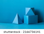 Small photo of Abstract geometrical figures still life composition. Three-dimensional prism pyramid rectangular cube objects on turquoise background. Platonic solids figures, selective focus