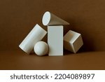 Small photo of White geometric shapes on a brown background. Platonic figures cube rectangle sphere prism, pyramid arranged in an abstract still life composition
