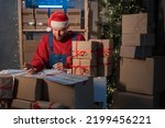 Small business owner delivery service and working packing box on Christmas, business owner santa claus working checking order to confirm before sending customer in post office, Shipment Online Sales.