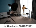 Photographer preparing for shooting by setting up equipment in home photo studio. Copy space
