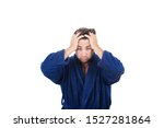 Small photo of Portrait of tardy young man wears blue bathrobe holding hands to head, unable to wake up in time to get to work, isolated on white background.