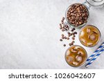 Cold brewed iced coffee in glass and coffee beans in glass jar on white background. Top view, copy space.