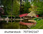 A red concrete bridge over a pond leading to a japanese garden at Duke University in Durham, North Carolina. Duke garden is one of the tourist attractions in the city, open to the public for free.