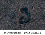 Child's footprint imprinted in the volcanic black sand of the Pacific Ocean in Guatemala, Central America.