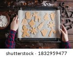 Christmas and New Year holidays, family celebration traditions. Mother cooking festive homemade sweets. Woman holding oven-tray with raw gingerbread cookies before baking