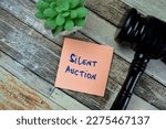 Concept of Silent Auction write on sticky notes with Gavel isolated on Wooden Table.