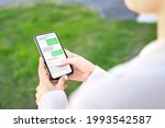 Woman texting with phone outdoors. Text message with smartphone. Digital sms and instant messaging chat. Person using cellphone in park outside in summer. Conversation with boyfriend or friend.