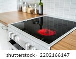 Stove and cooker red hot. Induction, ceramic cooktop, electric stovetop and hob in kitchen. Warm plate ready for cooking. Contemporary interior design, modern counter and wood table.