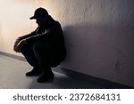 Small photo of Man with trauma, shame or anxiety. Sad desperate young guy or teenage boy. Drug addiction or despair. Criminal outcast or homeless person with stress in dark. Silhouette of victim of discrimination.
