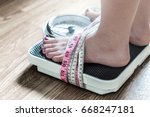 Feet tied up with measuring tape to a weight scale. Addiction and obsession to weight loss. Anorexia and eating disorder concept.