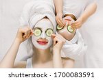 Mom and her 2 years old baby girl having fun together, making clay facial mask and cucumber slices on eyes. Mother with child doing beauty treatment together. Family time, spa and beauty, mothers day