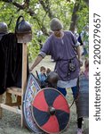Small photo of Russia, Gardarika - August 27, 2022: Fest of historical reconstruction Ural Fortress, Middle Ages and the Great Patriotic War, selective focus. Man in a squires suit and knights armor, vertical photo.