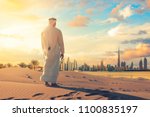 Arab man standing front Dubai skyline in the desert of UAE