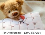 Close up of teddy bear holding callendar and paper red heart marking love day 14 february - Valentine's day concept