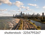 Downtown Chicago city skyline aerial centered over traffic along Lake Shore Drive between South Lagoon and Lake Michigan on a sunny day with fluffy white clouds in a blue sky above.