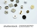 Small photo of Magnetic buttons for making wallets and backpacks. Magnetic button for fastening leather goods. Different types and colors of metal buttons on a white background. Sewing accessories for clothes.
