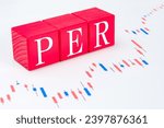 Small photo of A technical term of PER on wooden cubes on the candle chart, Price Earnings Ratio, Finance or stock background, Economy