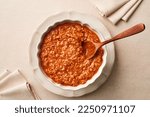A bowl of fresh BOLOGNESE SAUCE and a wooden spoon on a linen tablecloth.Studio shot. Top view.