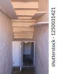 Small photo of White cupboard under stone stairs. A white wooden cupboard with shelving under stone stairs in an English workhouse.